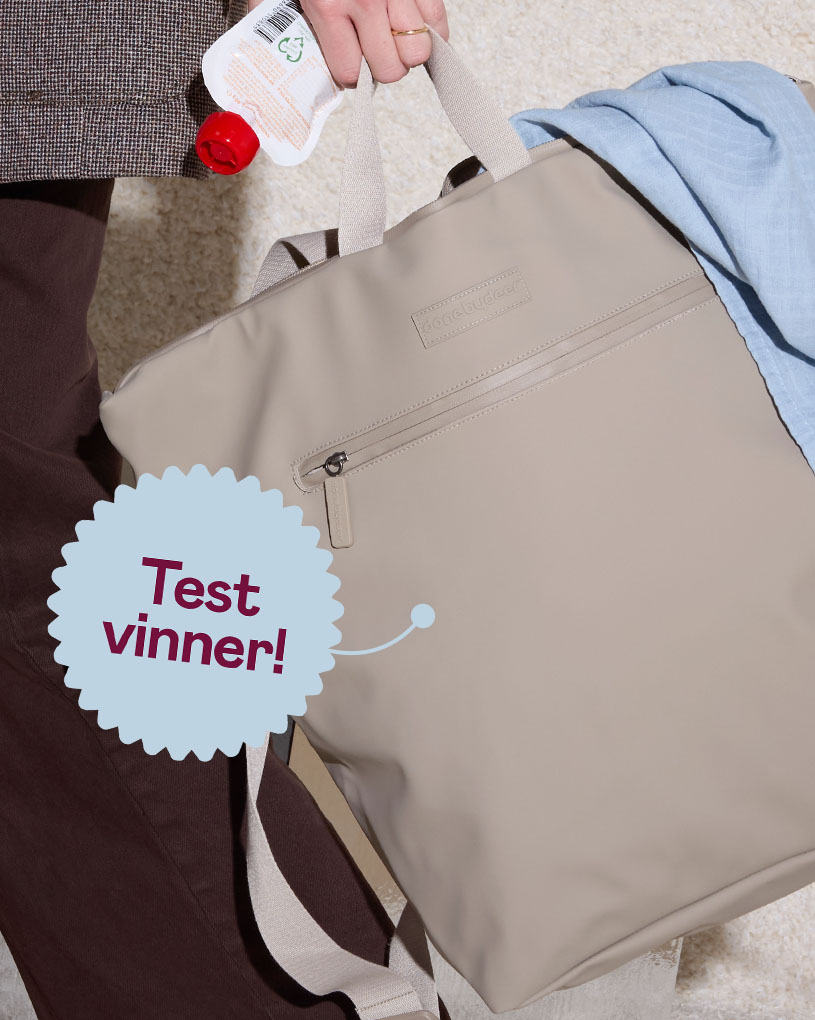 En person holder en beige stelleveske med teksten 'Best i test'.