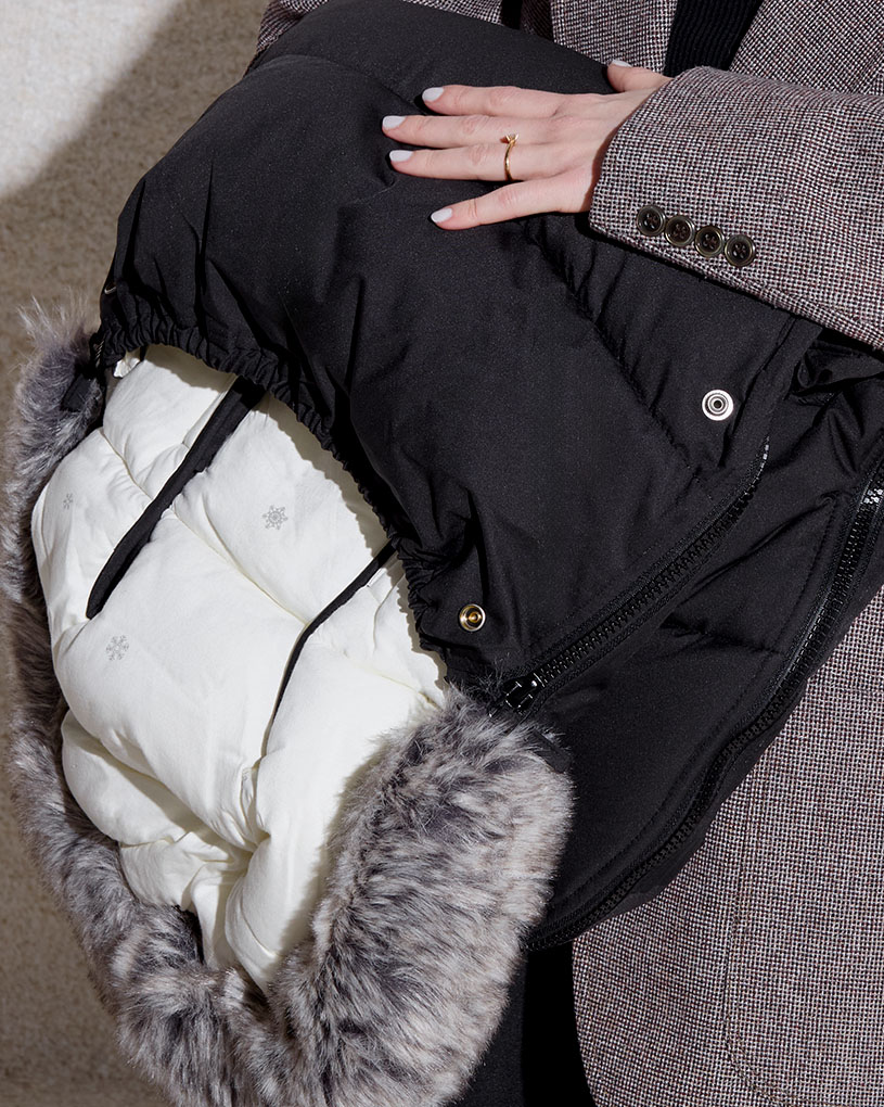 En svart sovepose med hvitt fôr og pelskant, med teksten 'BabyWeeks'.