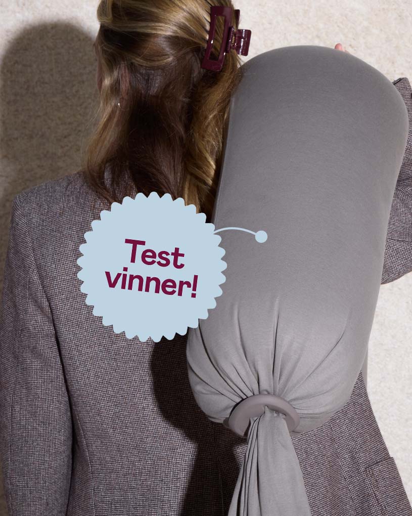 En kvinne bærer en grå graviditets- og ammesekk med teksten 'Best i test'.